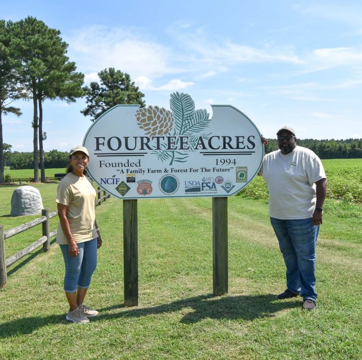 Edna and Tyrone Williams stand at the sign for their farm, Fourtee Acres.