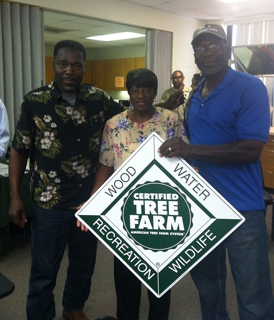 Mrs. Campbell and her family holding a Tree Farm sign. 