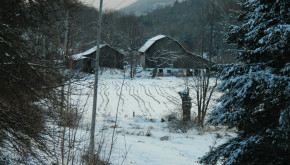 Snowy barns in forest and valley