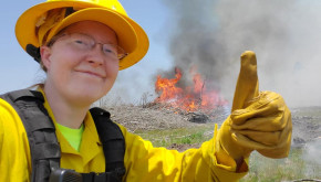 County Forester Regine Skelton giving a thumbs-up in front of a prescribed fire.
