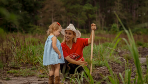 A woman and small girl work in the field.