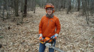 Woman wearing safety gear and holding a chainsaw.